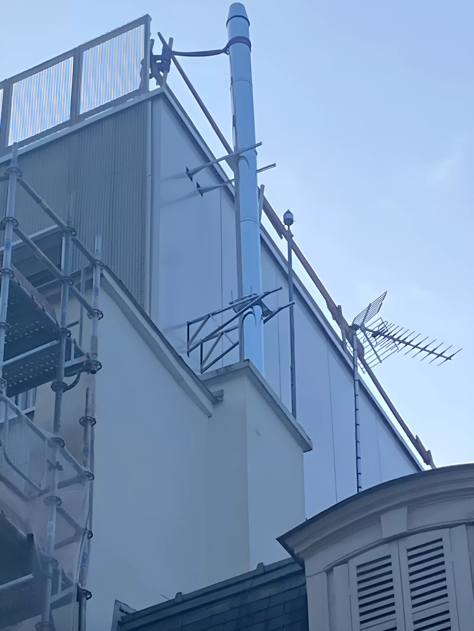 Antenne sur mât et caméra en rive de toiture d'immeuble