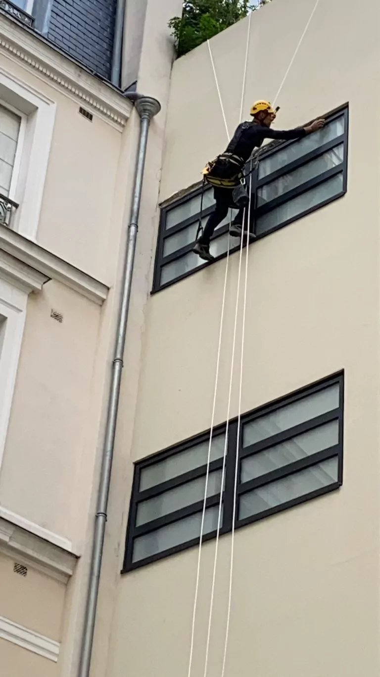 Cordiste au travail sur les fenêtres d'une façade sur cour