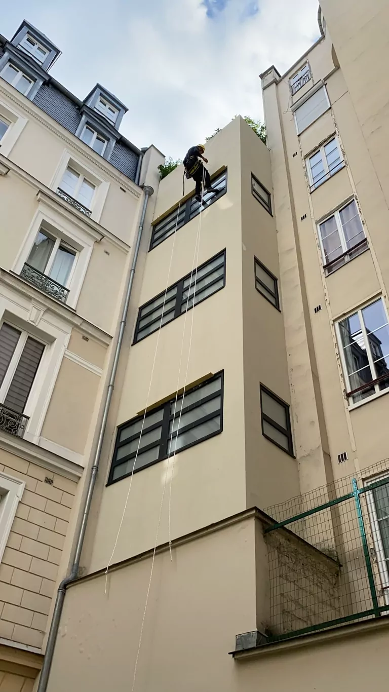 Cordiste en façade dans une cour d'immeuble parisien
