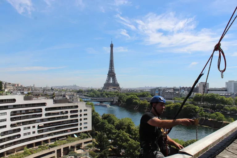 Cordiste installant les cordes avec vue sur la Tour Eiffel