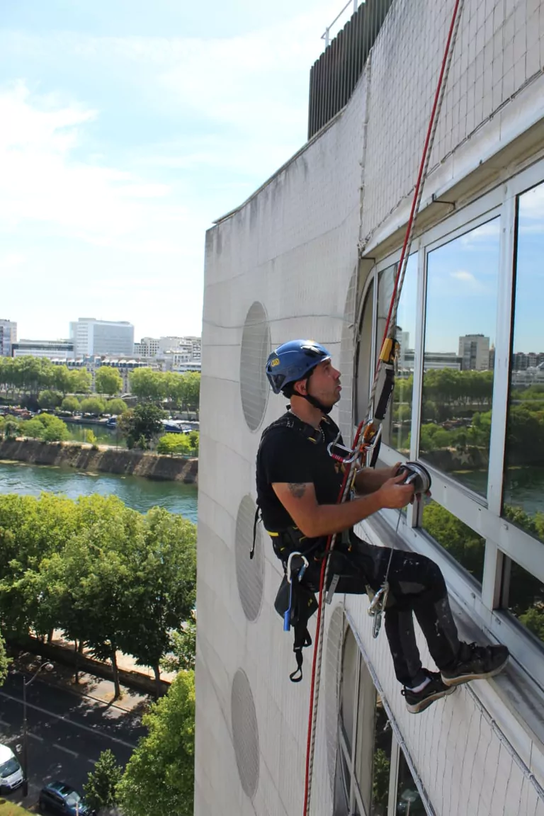 Intervention de cordiste sur façade vitrée au bord de la Seine