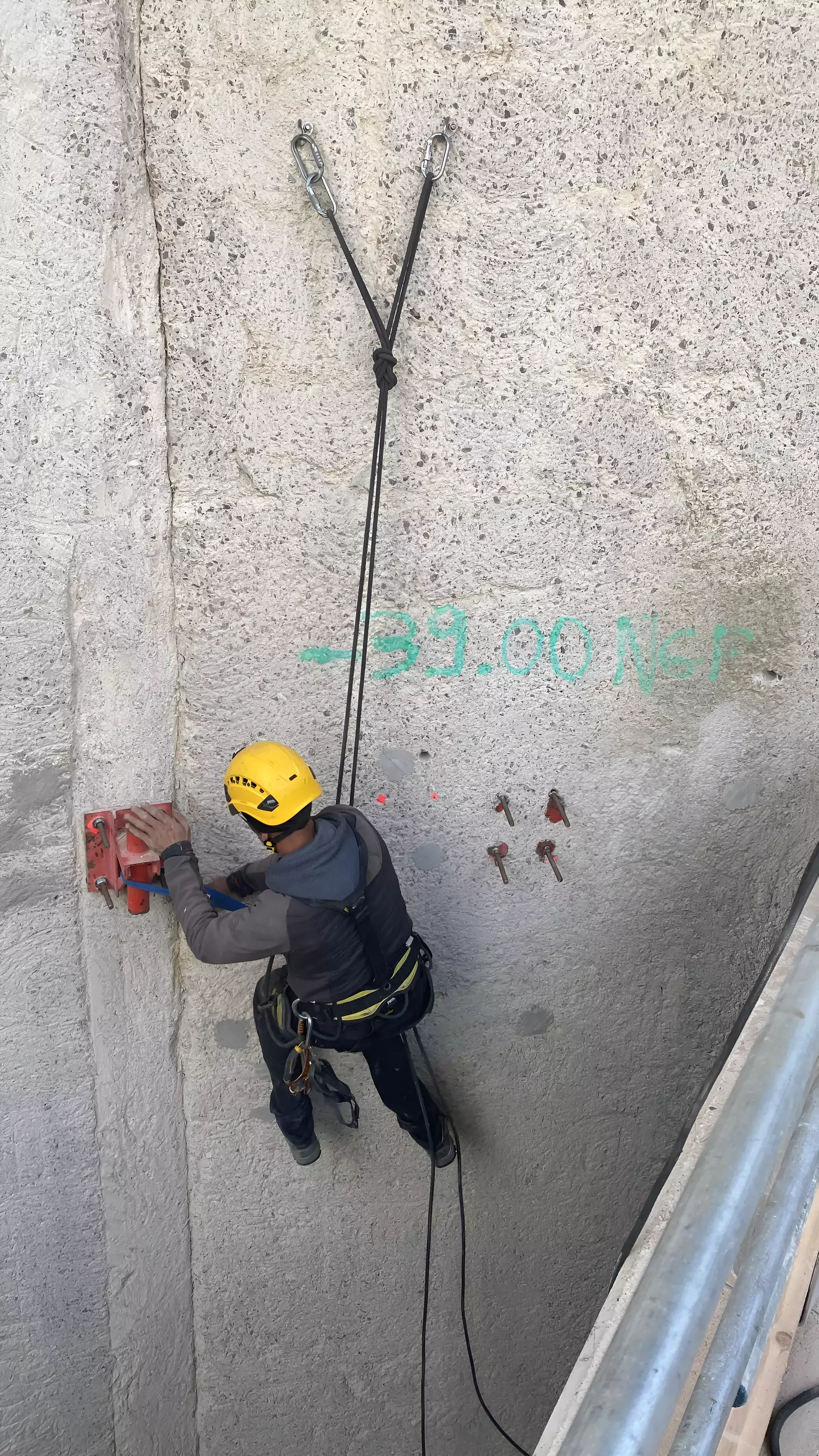 Cordiste au contact d'une façade en béton, relevés tracés sur le mur