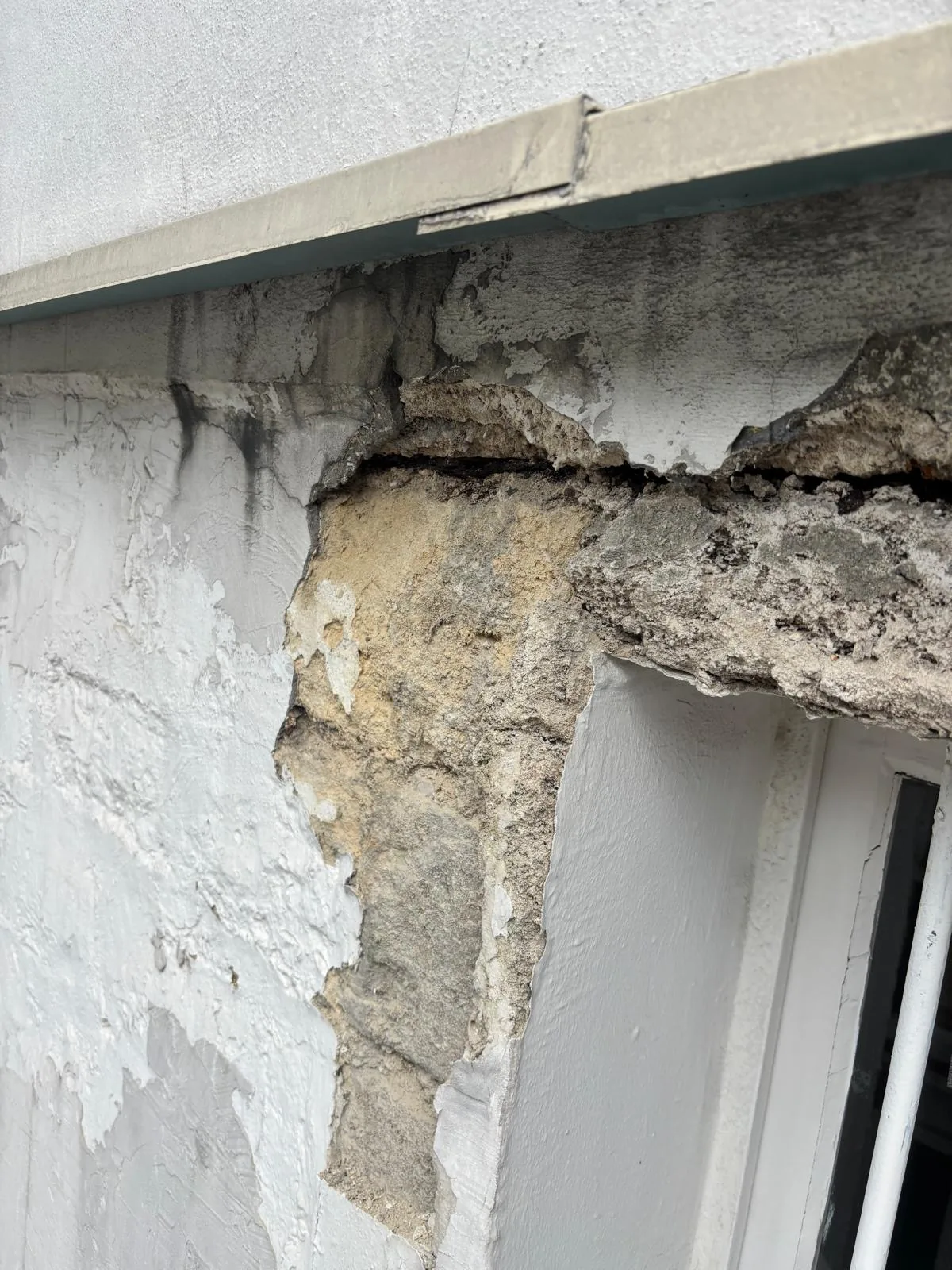 Bandeau de béton fissuré au-dessus d'une fenêtre, enduit tombé : le type de désordre visé par un arrêté de mise en sécurité