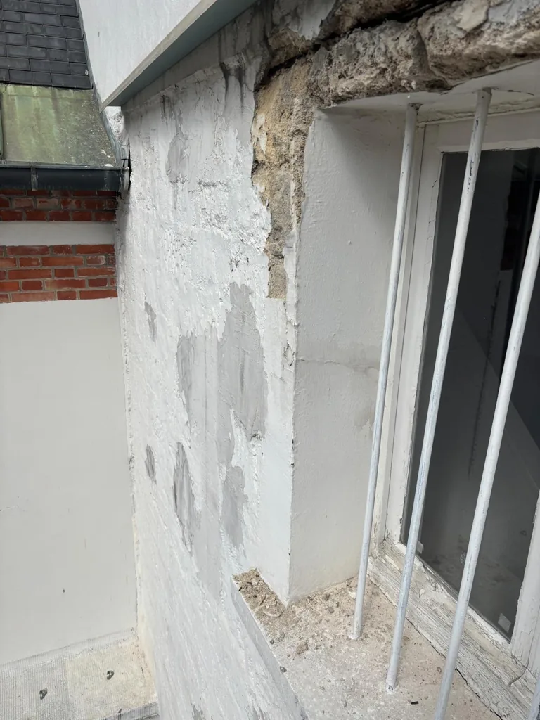 Enduit tombé et béton mis à nu sur une façade