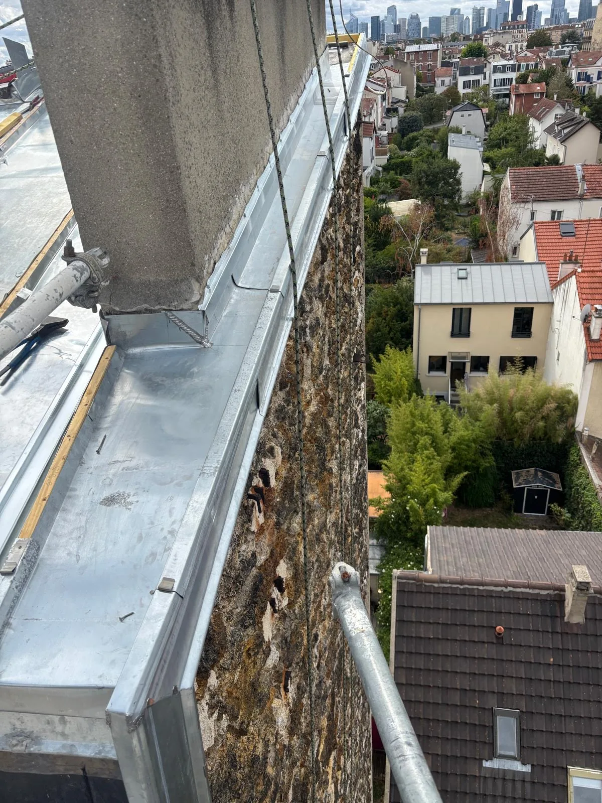 Chéneau et tête de mur en zinc vus depuis les cordes au-dessus des toits d'Île-de-France : les points par où l'eau entre dans un immeuble