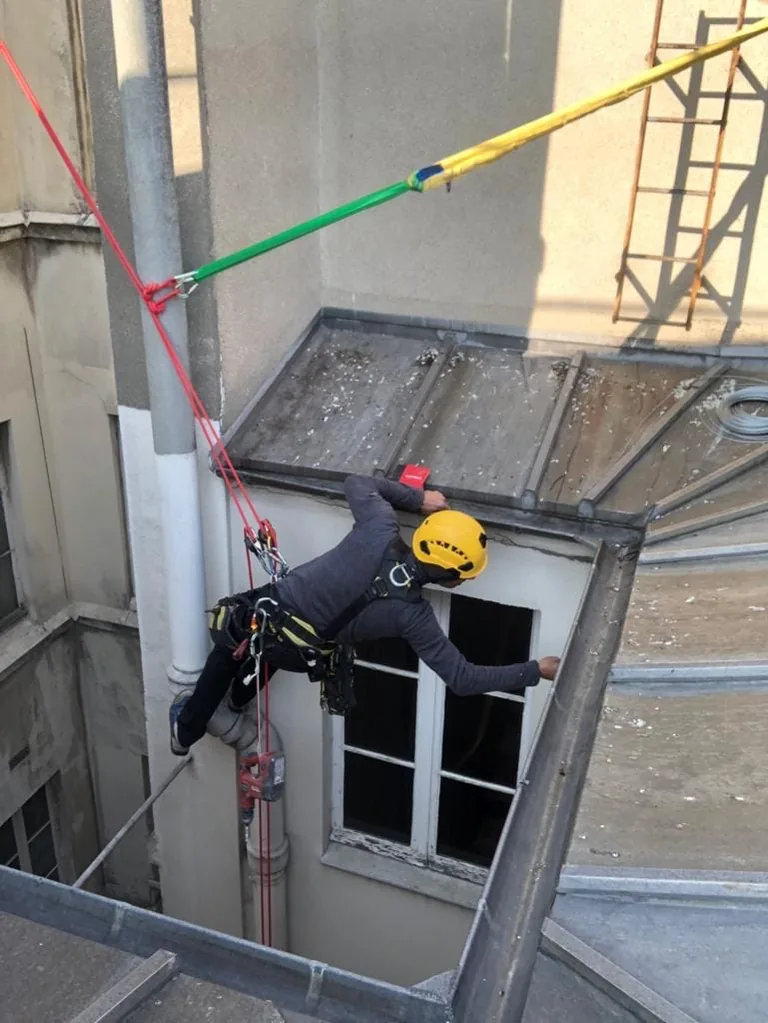 Cordiste dans une cour d'immeuble parisien, cordes et ligne de vie en place