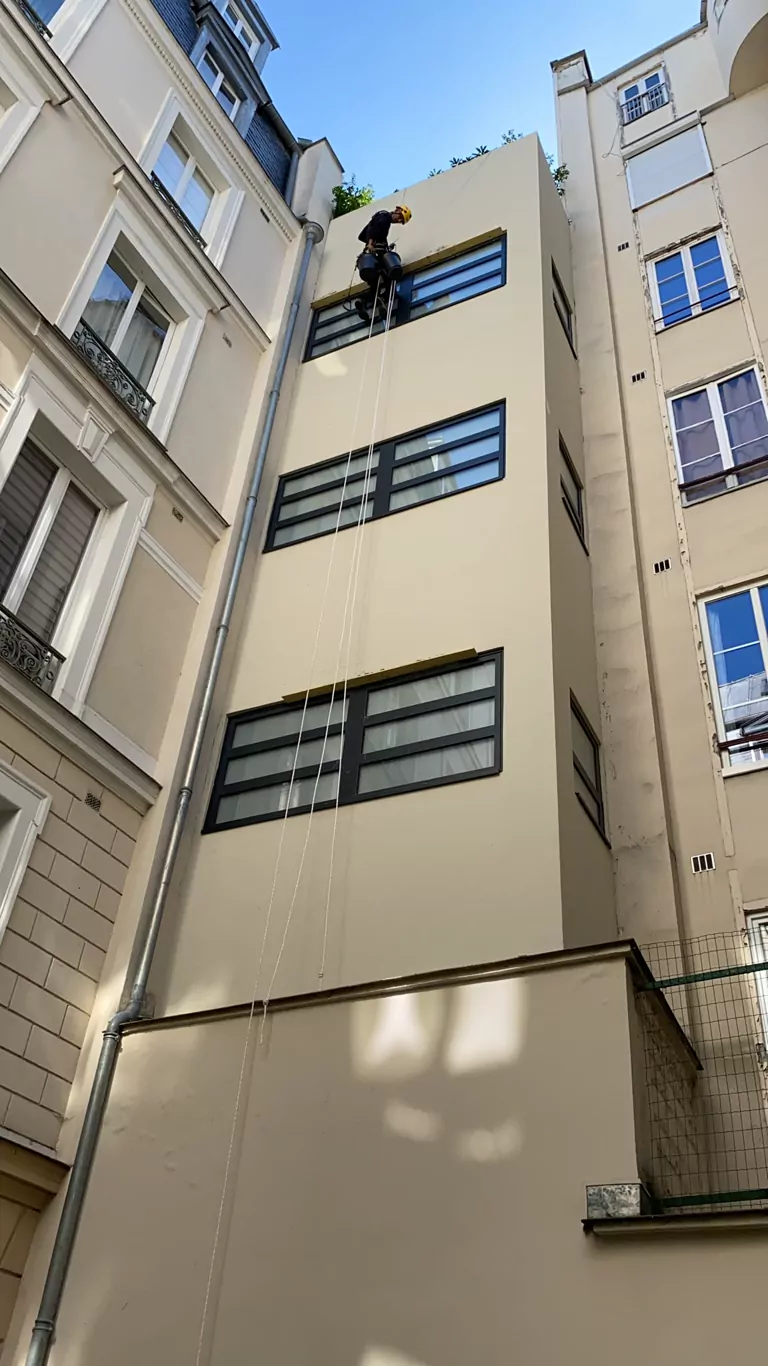 Cordiste en intervention sur la façade d'une cour d'immeuble à Paris