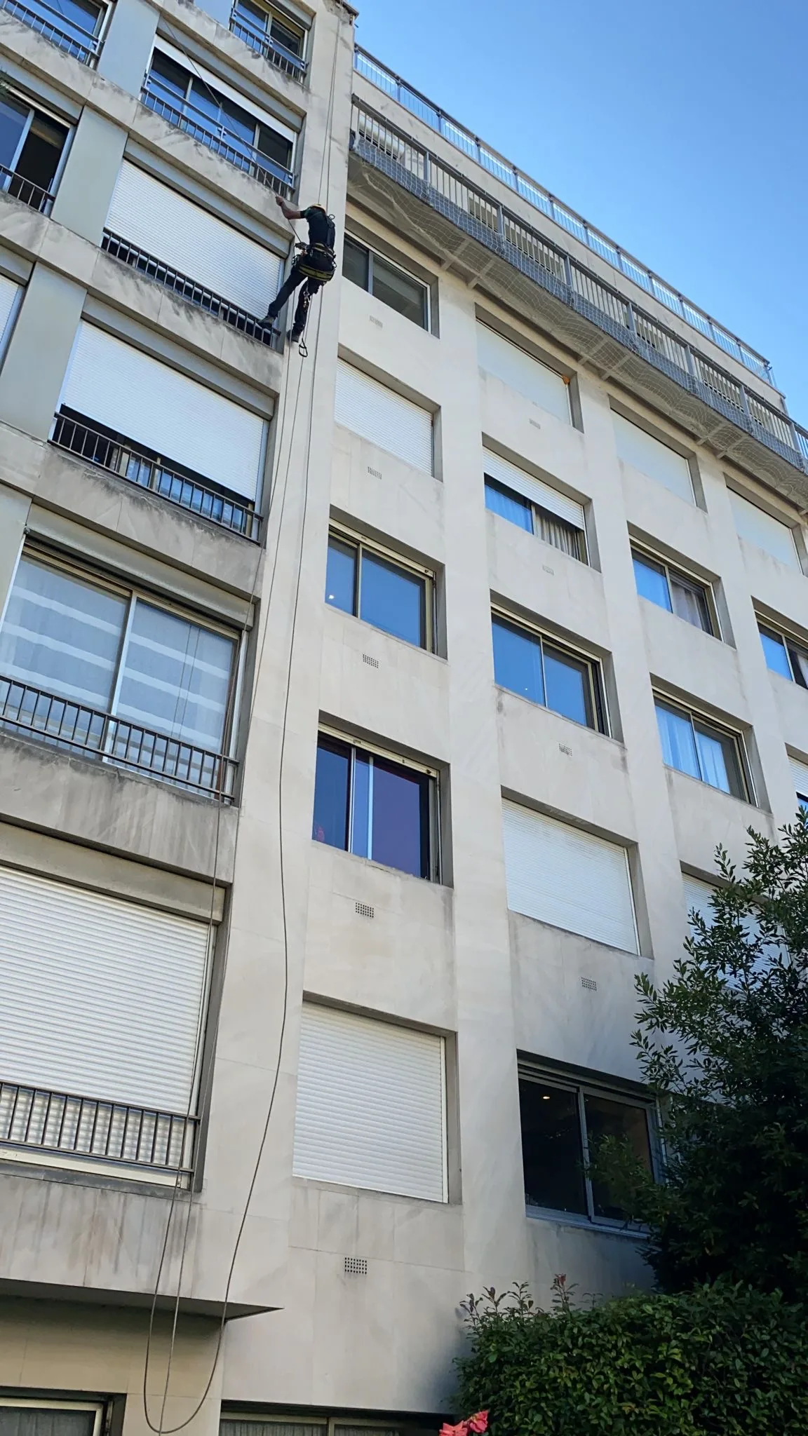 Cordiste en descente sur la façade d'un immeuble résidentiel