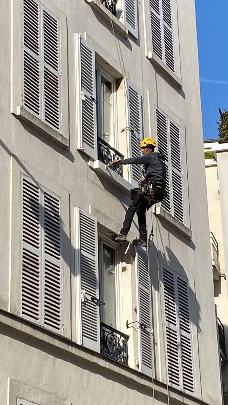 Cordiste travaillant sur la façade d'un immeuble parisien