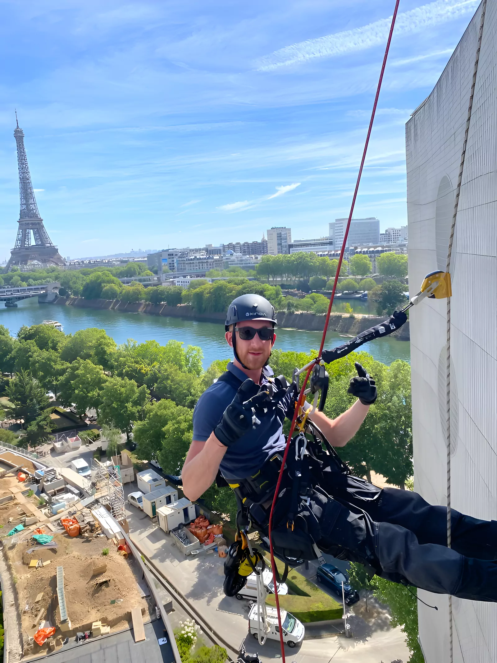 Cordiste suspendu sur une façade face à la tour Eiffel