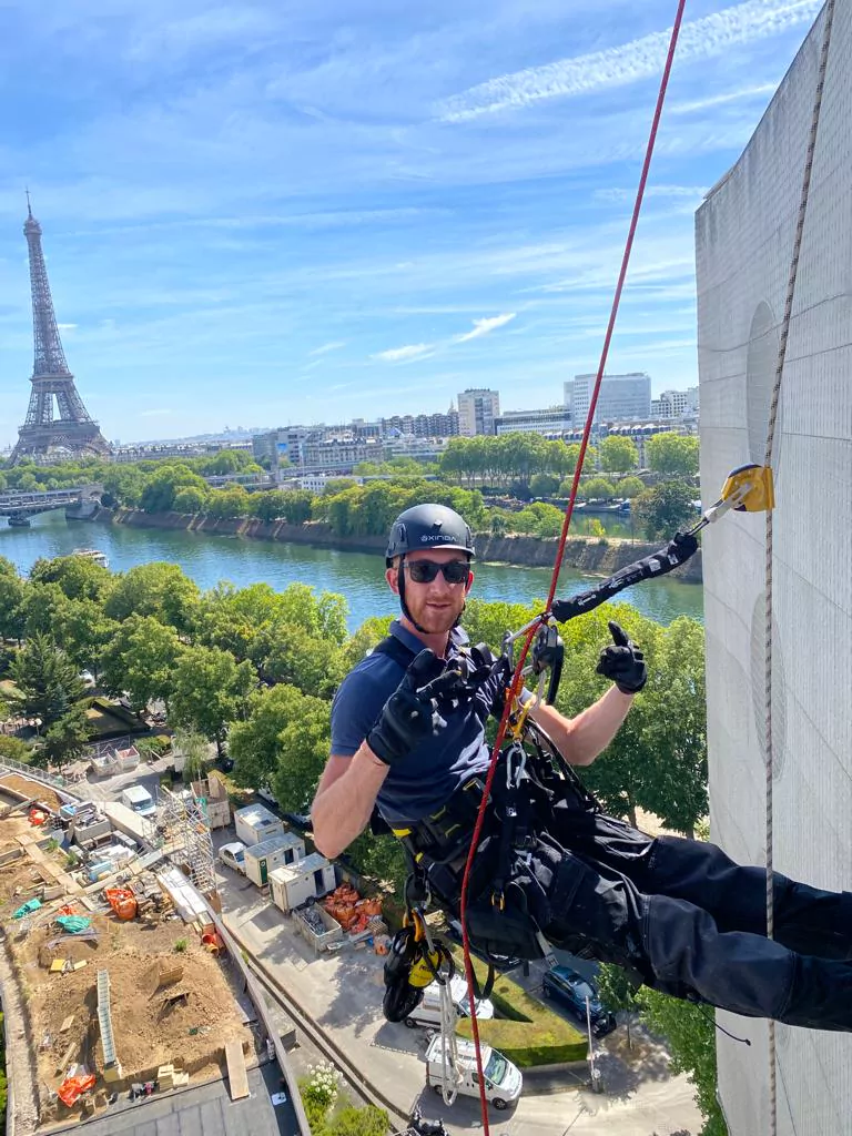 Cordiste suspendu sur façade avec vue sur la Tour Eiffel, Paris 15e