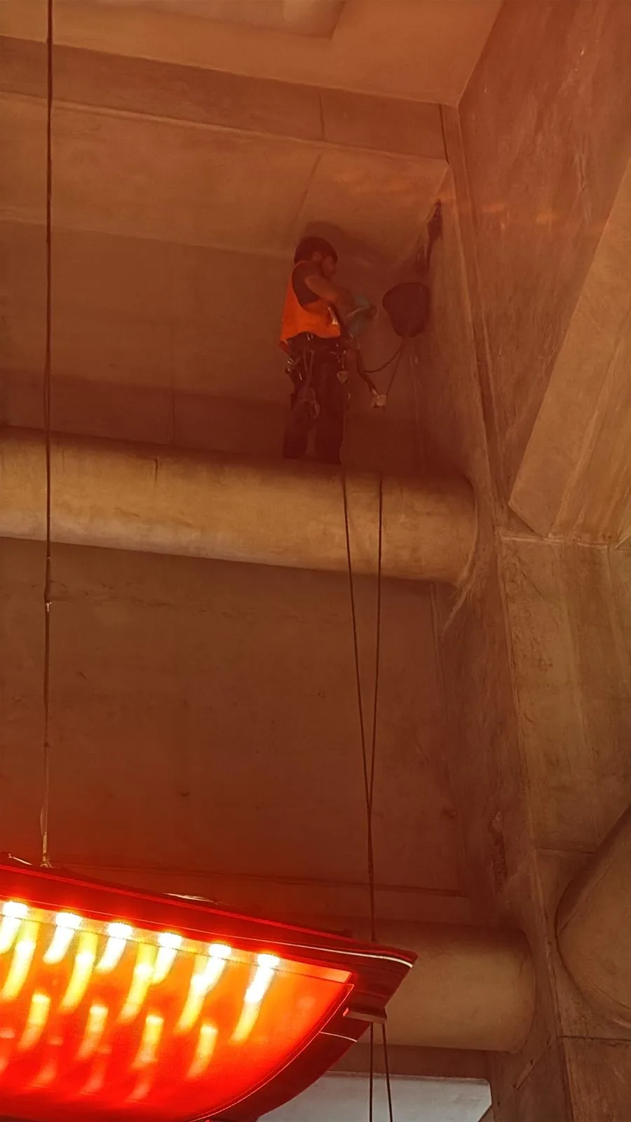 Cordiste suspendu sur deux cordes ancrées séparément sous un ouvrage en béton, sur des ancrages installés pour l'intervention