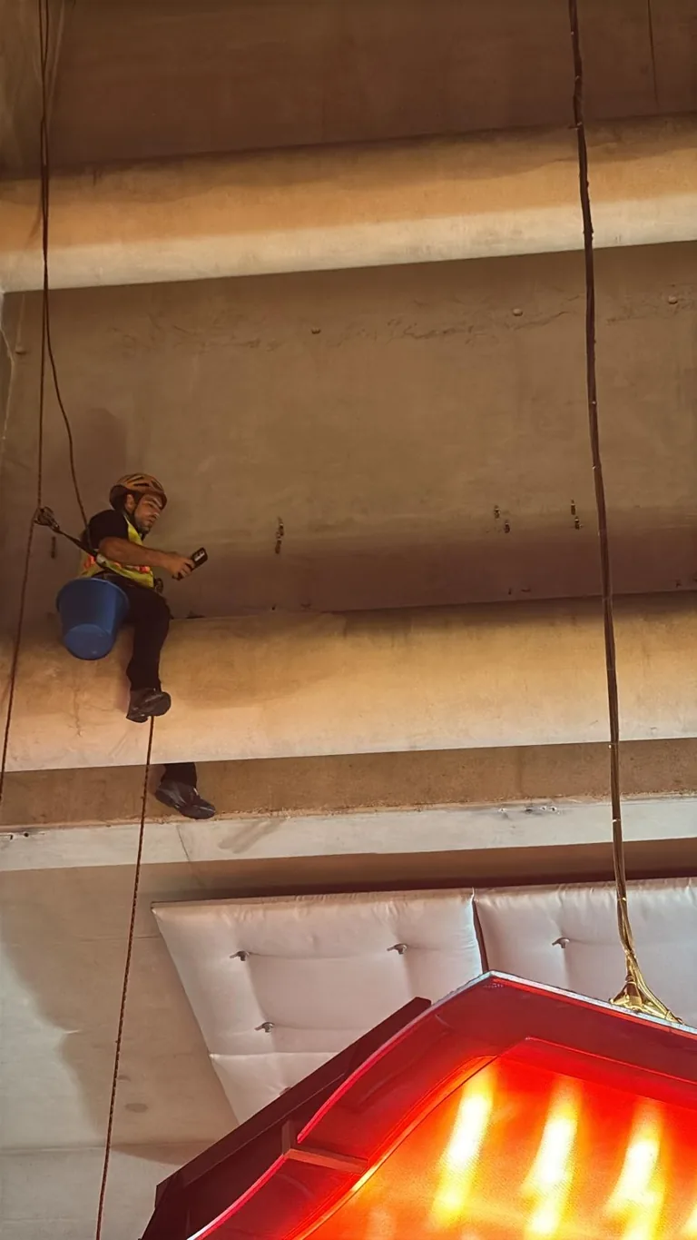 Cordiste en suspension sous une dalle de béton, outils attachés au harnais