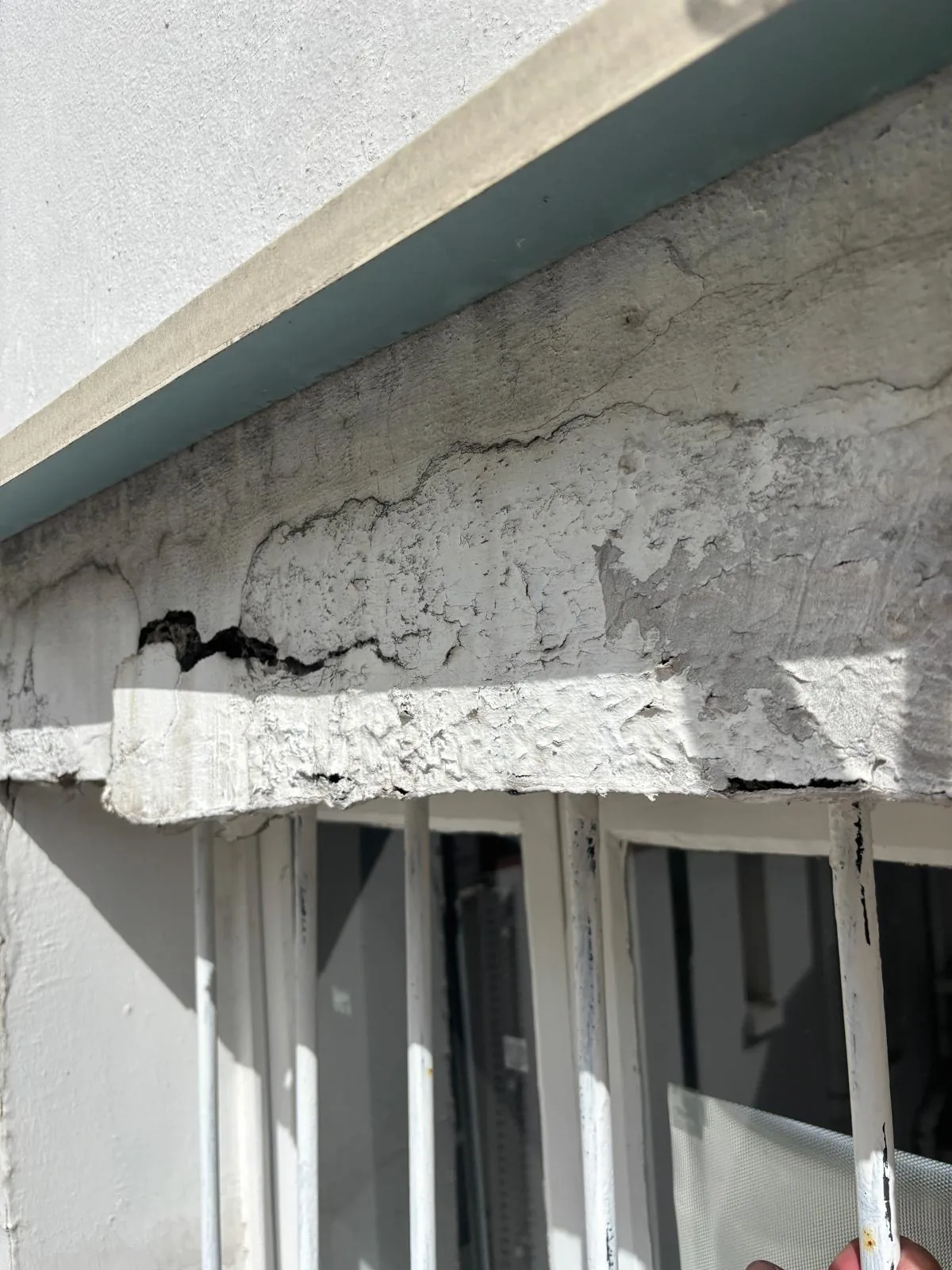 Corniche en béton fissurée sur toute sa longueur au-dessus des fenêtres