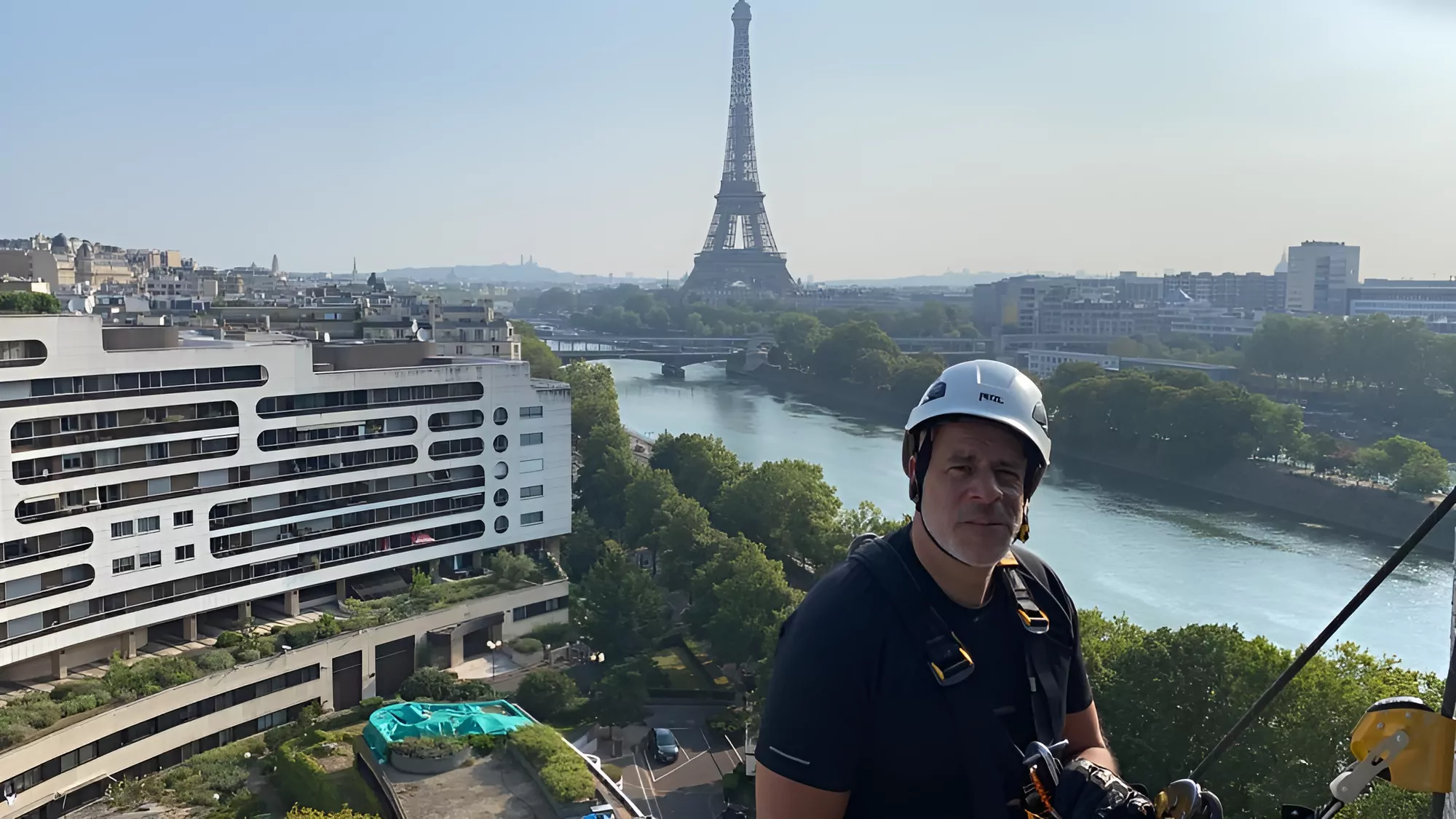 Cordiste sur un toit face à la Seine et à la tour Eiffel