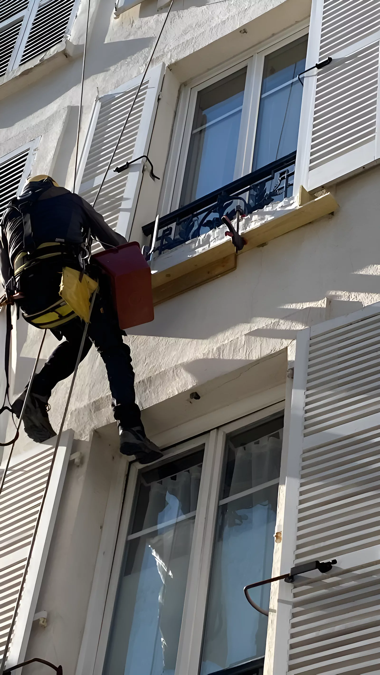 Cordiste intervenant sur la façade d'un immeuble haussmannien à Paris