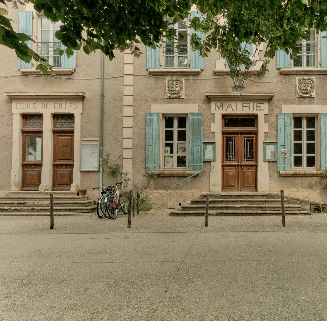 Façade d'une mairie de commune, inscription Mairie au-dessus de la porte, volets et drapeaux
