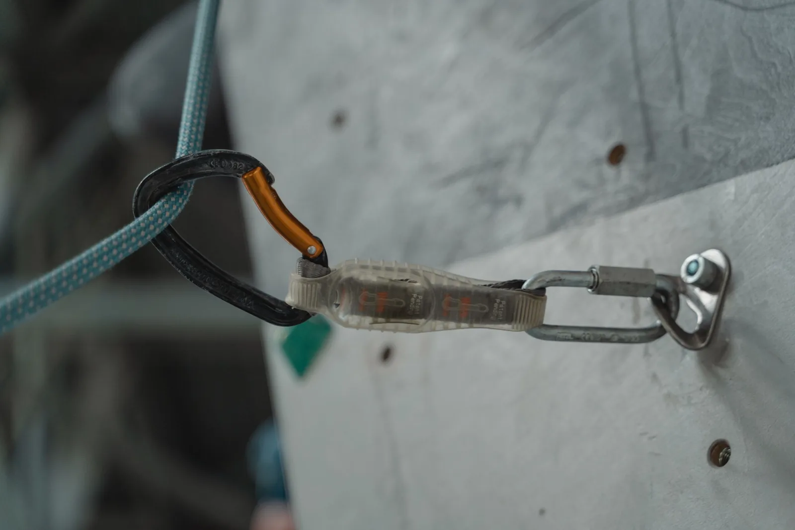 Point d'ancrage antichute sur un mur en béton : platine boulonnée, connecteur et longe accrochés pour la vérification