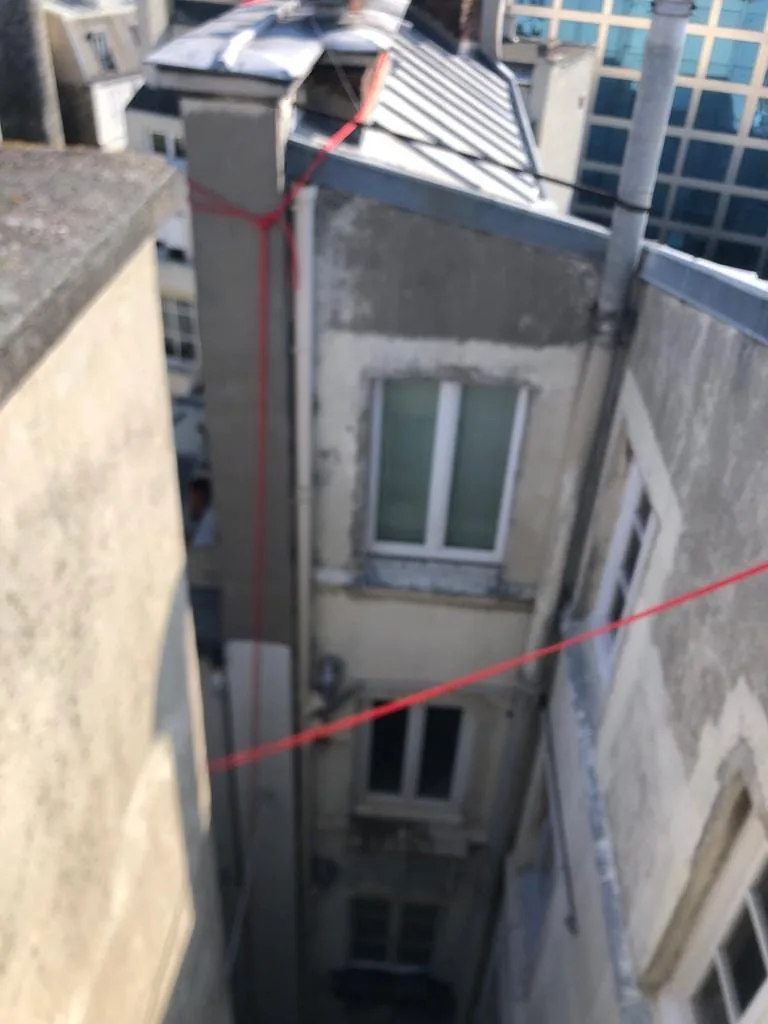 Souches de cheminée et toiture en zinc vues depuis les cordes, dans une cour parisienne