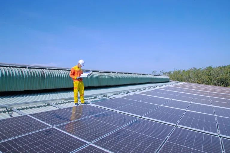 Technicien sur le cheminement d'une toiture bac acier équipée de panneaux photovoltaïques